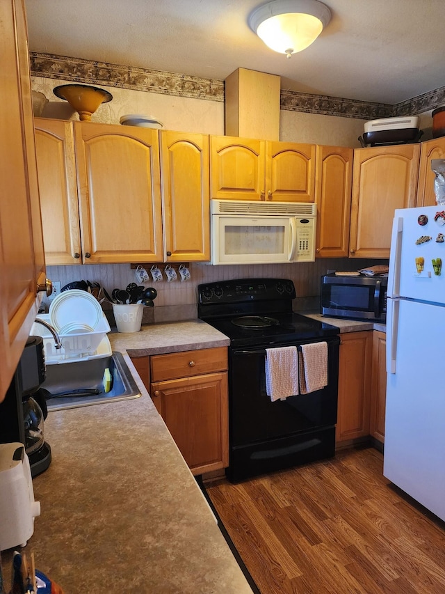 kitchen with dark hardwood / wood-style flooring, white appliances, and sink