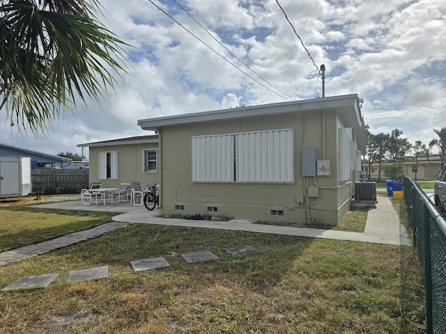 rear view of house with central AC unit, a yard, and a patio