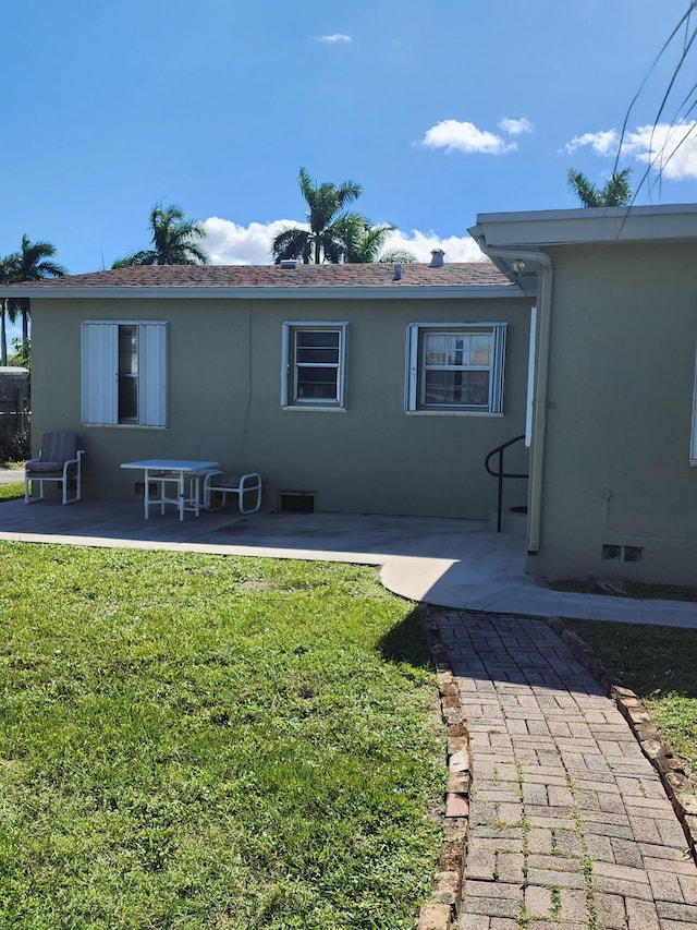 back of property with a lawn and a patio