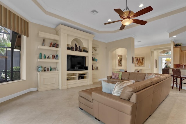 tiled living room featuring built in shelves, ceiling fan, and ornamental molding