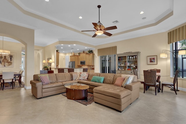 living room featuring ceiling fan, light tile patterned flooring, crown molding, and a tray ceiling