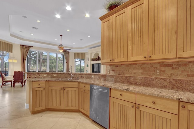 kitchen featuring decorative backsplash, light brown cabinetry, stainless steel dishwasher, a tray ceiling, and sink