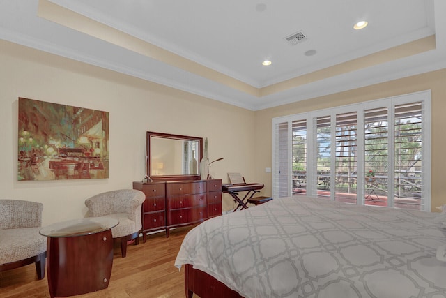 bedroom featuring light wood-type flooring, a raised ceiling, and crown molding