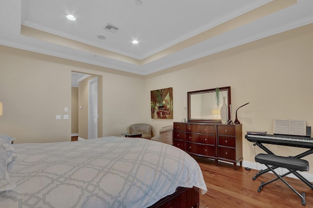 bedroom featuring hardwood / wood-style flooring, a raised ceiling, and ornamental molding