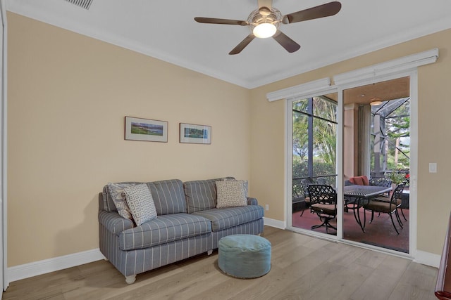 living room featuring light wood-type flooring, ceiling fan, and ornamental molding