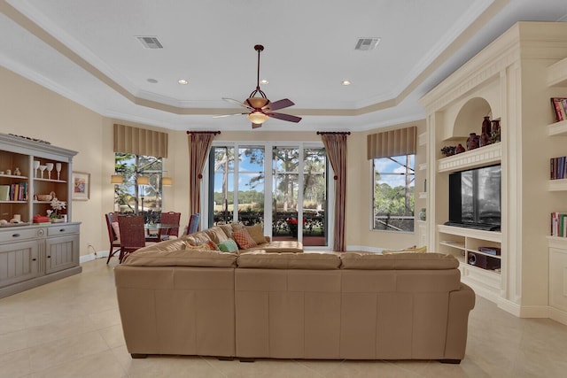 tiled living room featuring ceiling fan, a raised ceiling, built in features, and crown molding