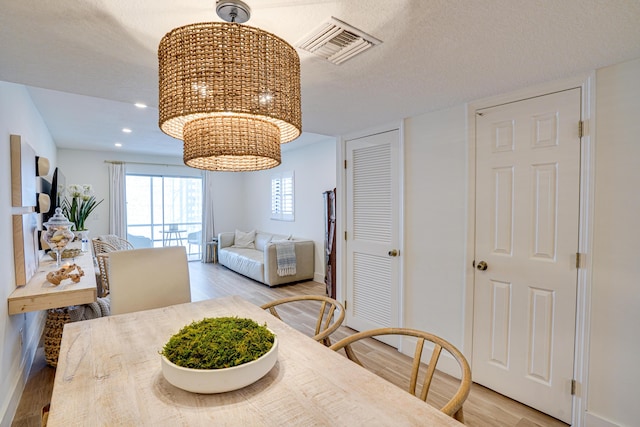 dining space featuring a textured ceiling and light hardwood / wood-style flooring