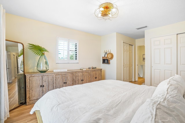 bedroom featuring light hardwood / wood-style floors and multiple closets