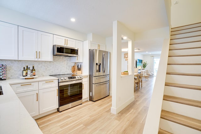 kitchen with decorative backsplash, light hardwood / wood-style flooring, white cabinets, and stainless steel appliances