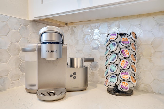 interior space featuring decorative backsplash, white cabinetry, and light stone counters