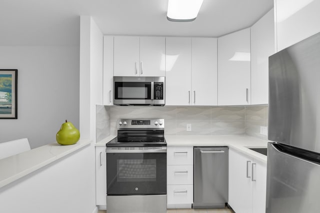 kitchen with white cabinets, appliances with stainless steel finishes, and decorative backsplash