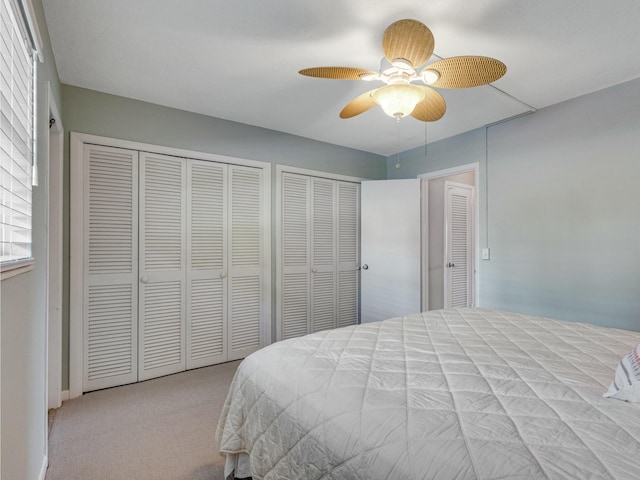 carpeted bedroom with ceiling fan and two closets