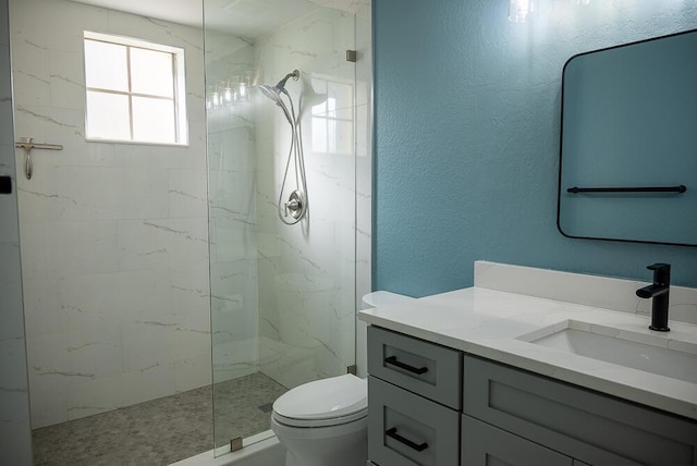 bathroom featuring vanity, a tile shower, and toilet