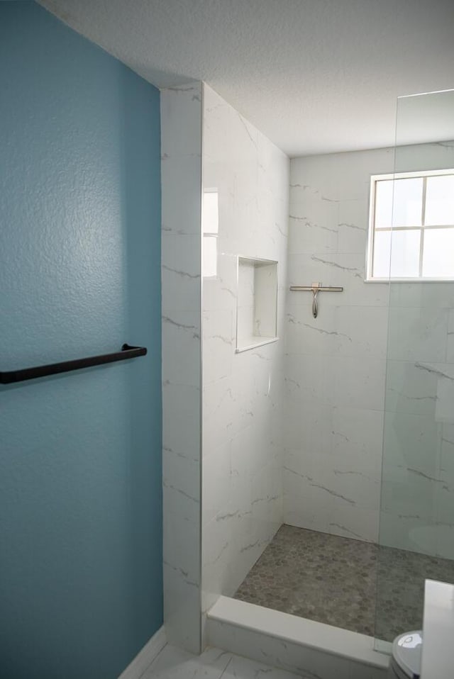 bathroom featuring a tile shower and toilet