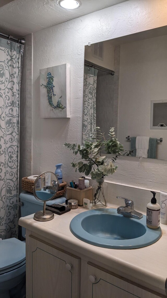 full bathroom with visible vents, a textured wall, vanity, and toilet