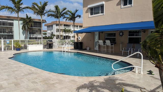 pool featuring grilling area, a patio area, and fence