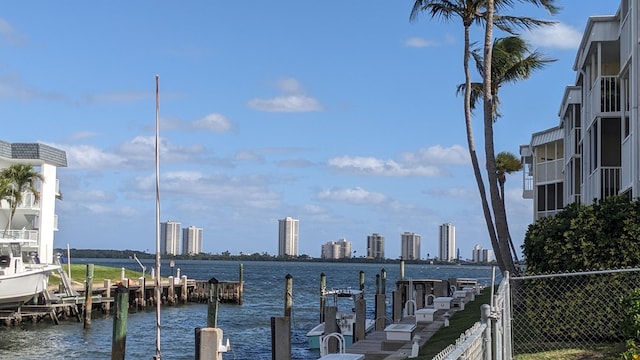 water view with a boat dock, fence, and a city view