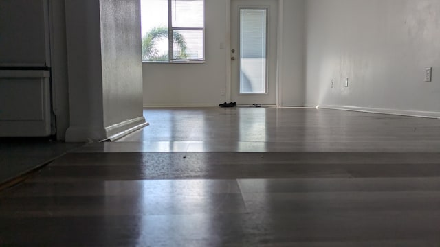 spare room with baseboards and wood finished floors