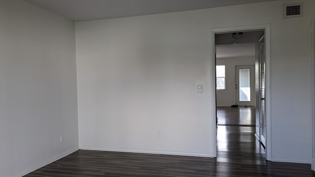 spare room featuring baseboards, visible vents, and dark wood-type flooring