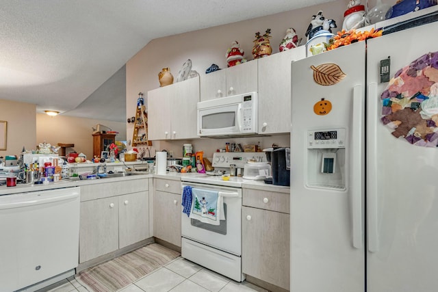 kitchen featuring a textured ceiling, sink, light tile patterned floors, and white appliances