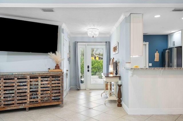 tiled foyer featuring a notable chandelier and ornamental molding