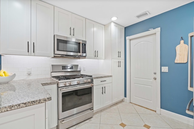 kitchen featuring white cabinets, appliances with stainless steel finishes, tasteful backsplash, and light stone counters