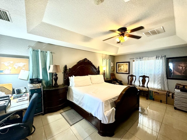 bedroom featuring a raised ceiling, ceiling fan, and a textured ceiling