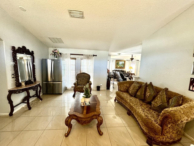 living room featuring ceiling fan, light tile patterned floors, and a textured ceiling