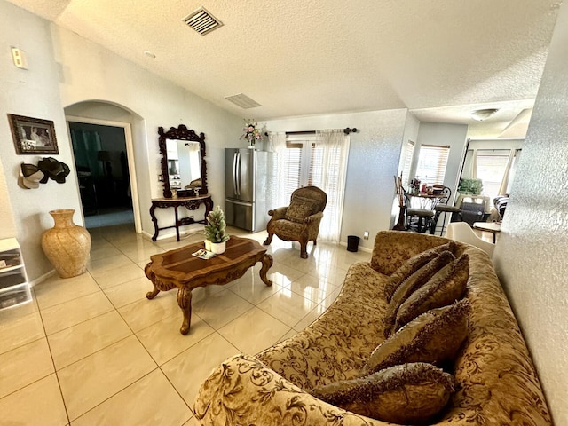 tiled living room with a textured ceiling and vaulted ceiling