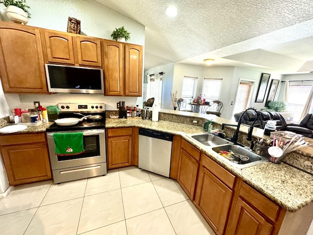 kitchen with kitchen peninsula, appliances with stainless steel finishes, a textured ceiling, and sink