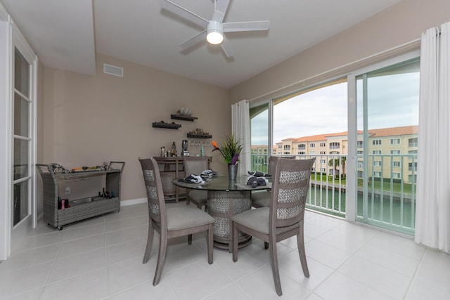 dining space with light tile patterned floors, a water view, and ceiling fan