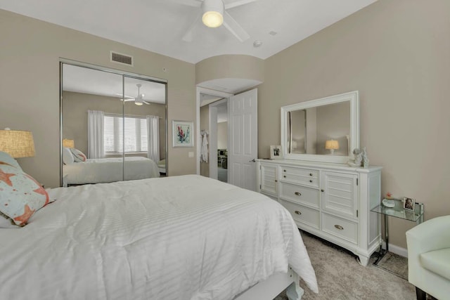 bedroom with ceiling fan, light carpet, and a closet