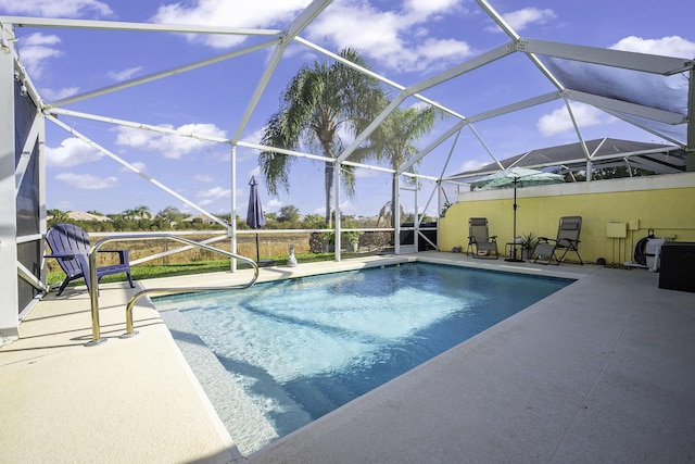 view of pool with glass enclosure and a patio