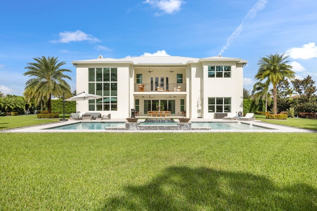 rear view of house with ceiling fan, a yard, a balcony, and a patio