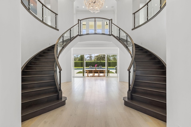 entryway with light wood-type flooring, a towering ceiling, a chandelier, and ornamental molding