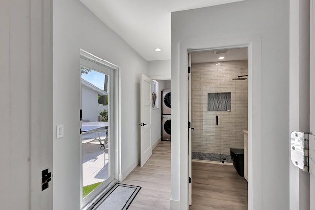 hall featuring light wood-type flooring and stacked washer / dryer