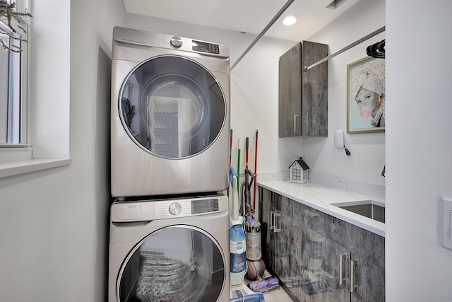 laundry room featuring cabinets and stacked washing maching and dryer