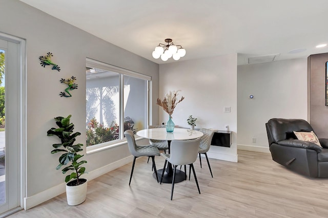 dining room with light hardwood / wood-style flooring and a notable chandelier