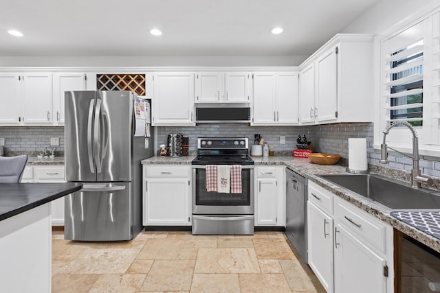 kitchen with appliances with stainless steel finishes, tasteful backsplash, white cabinetry, and sink