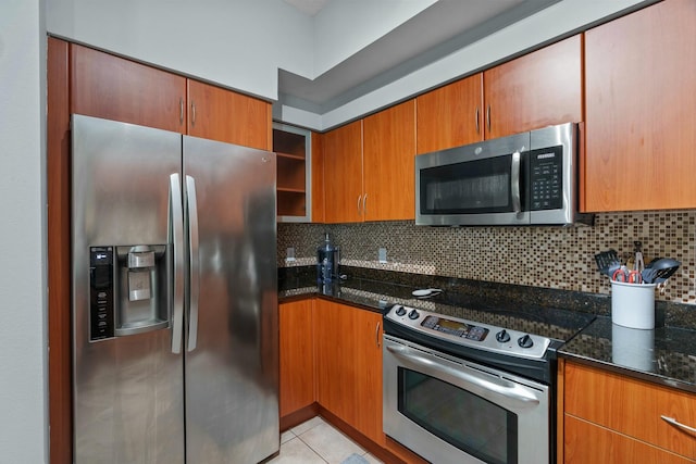 kitchen with appliances with stainless steel finishes, tasteful backsplash, light tile patterned floors, and dark stone countertops