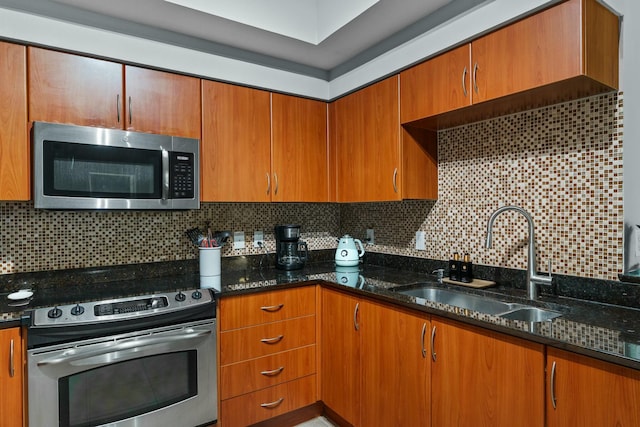 kitchen featuring dark stone counters, backsplash, sink, and stainless steel appliances