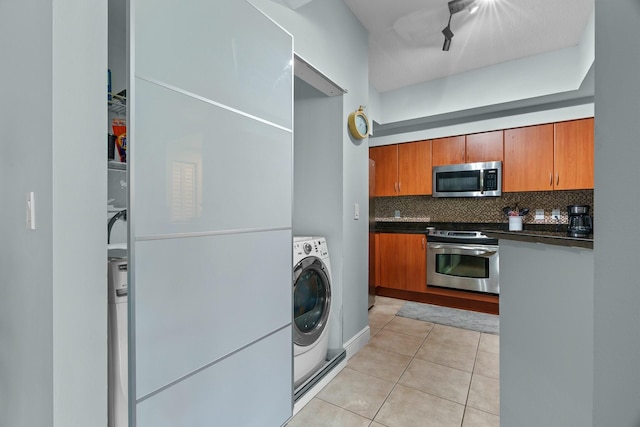 kitchen featuring backsplash, washer / clothes dryer, light tile patterned flooring, and appliances with stainless steel finishes