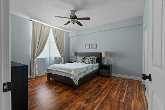 bedroom with a textured ceiling, ceiling fan, and dark wood-type flooring