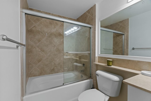 full bathroom with combined bath / shower with glass door, vanity, and toilet