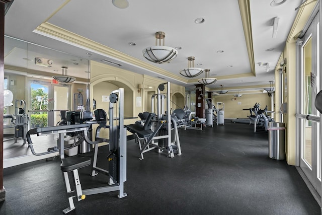 gym featuring a raised ceiling and ornamental molding