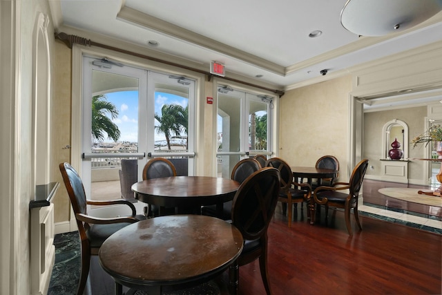 dining space with a raised ceiling, wood-type flooring, a wealth of natural light, and french doors