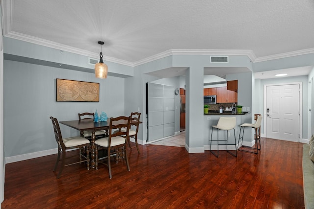 dining space featuring a textured ceiling, hardwood / wood-style flooring, and crown molding