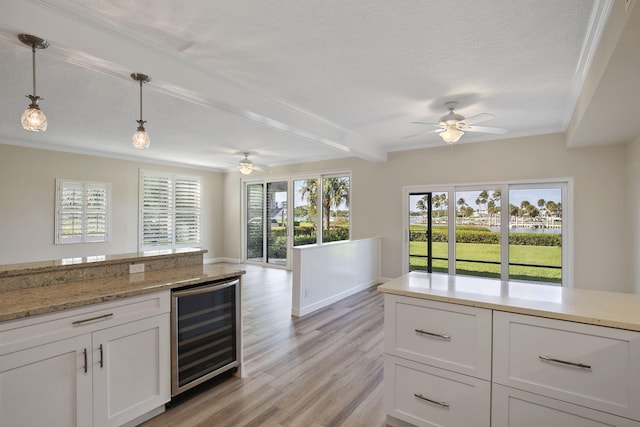 kitchen with beverage cooler, pendant lighting, a textured ceiling, light hardwood / wood-style floors, and white cabinets