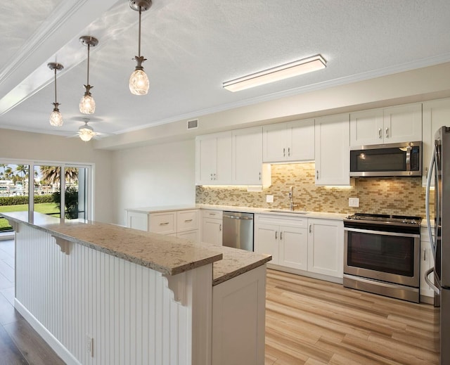 kitchen featuring stainless steel appliances, sink, pendant lighting, white cabinets, and light hardwood / wood-style floors