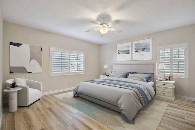 bedroom with ceiling fan, light hardwood / wood-style floors, and a textured ceiling